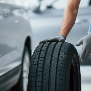 Mechanic holding a tire at the repair garage. Replacement of winter and summer tires